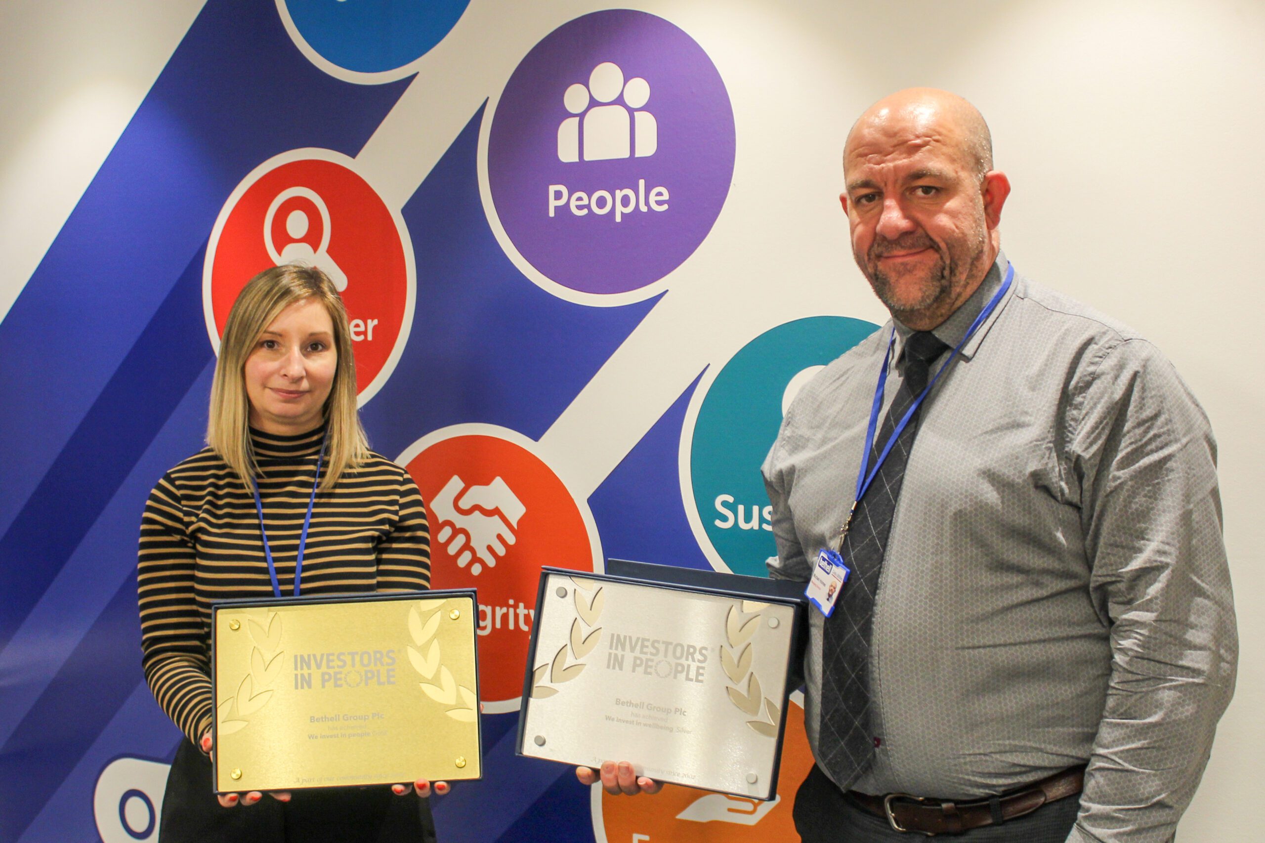 Two people with gold and silver awards