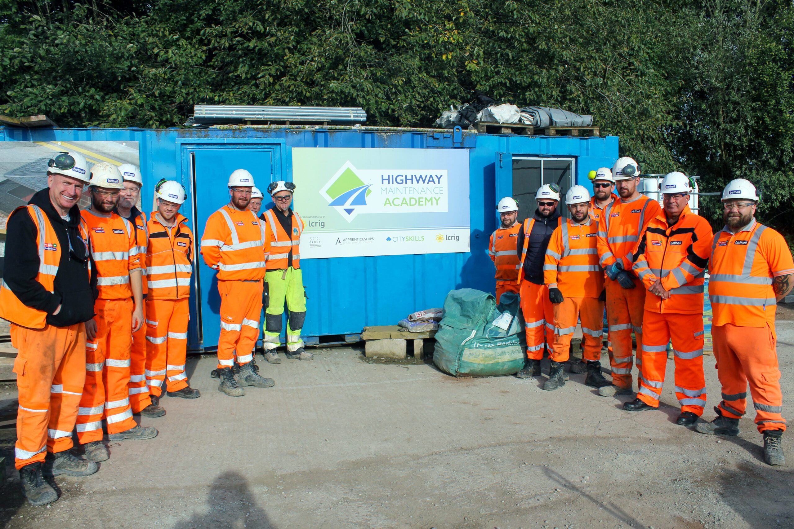 A group of operatives in orange PPE outside a training academy