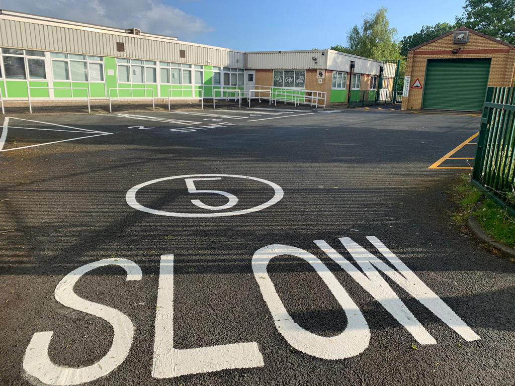 A car park with a large 5mph speed limit and SLOW sign
